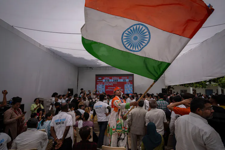 Supporters of the India Congress Party wave flags as they watch the election count, Jue 2024.