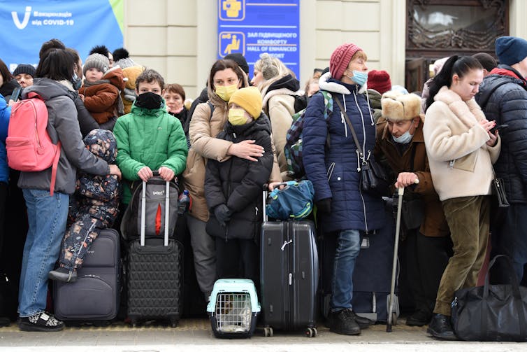 A group of Ukrainian people with luggage, waiting at a train station