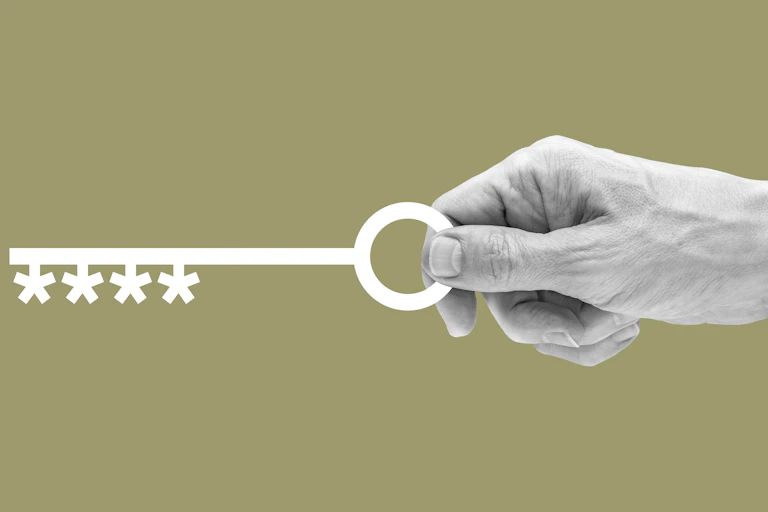 A human hand holding a key whose base is shaped like the asterisks in a password