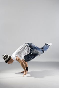 A dancer posed with two bent arms on the ground holding up his weight, with legs outstretched.