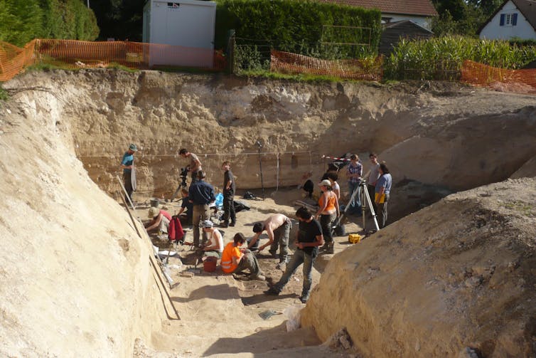 Des archéologues fouillent sur le terrain dans une large tranchée creusée dans le sol calcaire