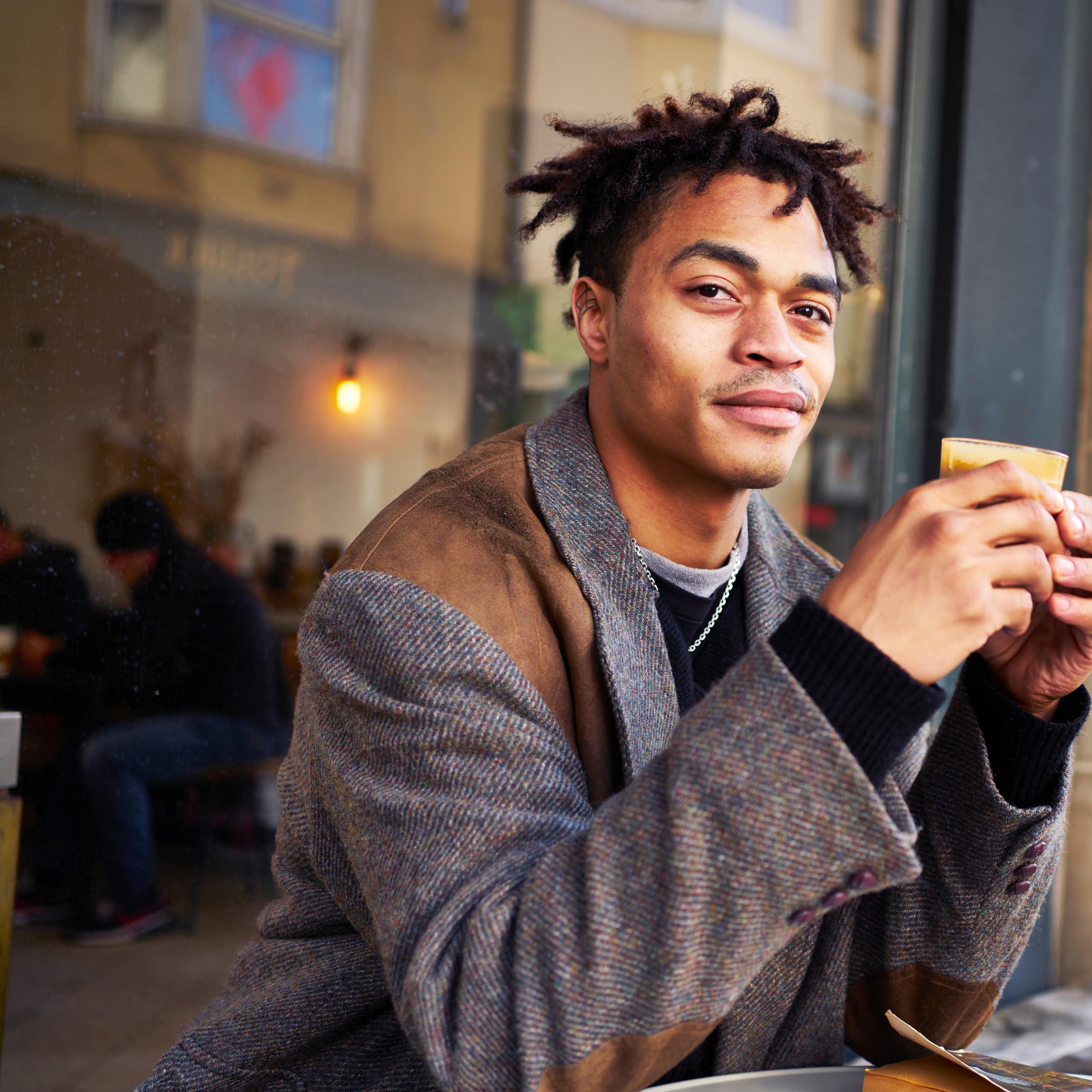 Fashionable young man drinking coffee at a cafe outdoors.