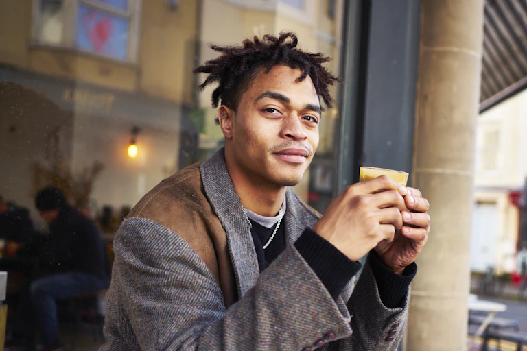 Fashionable young man drinking coffee at a cafe outdoors.