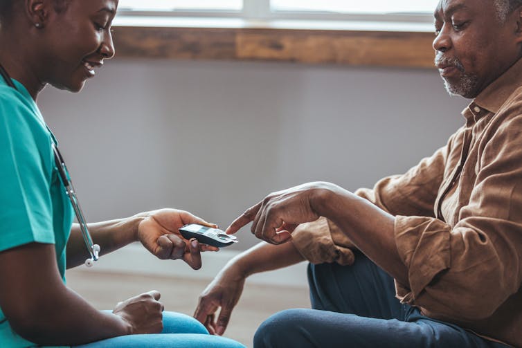 A man having his blood sugar measured by a health-care worker