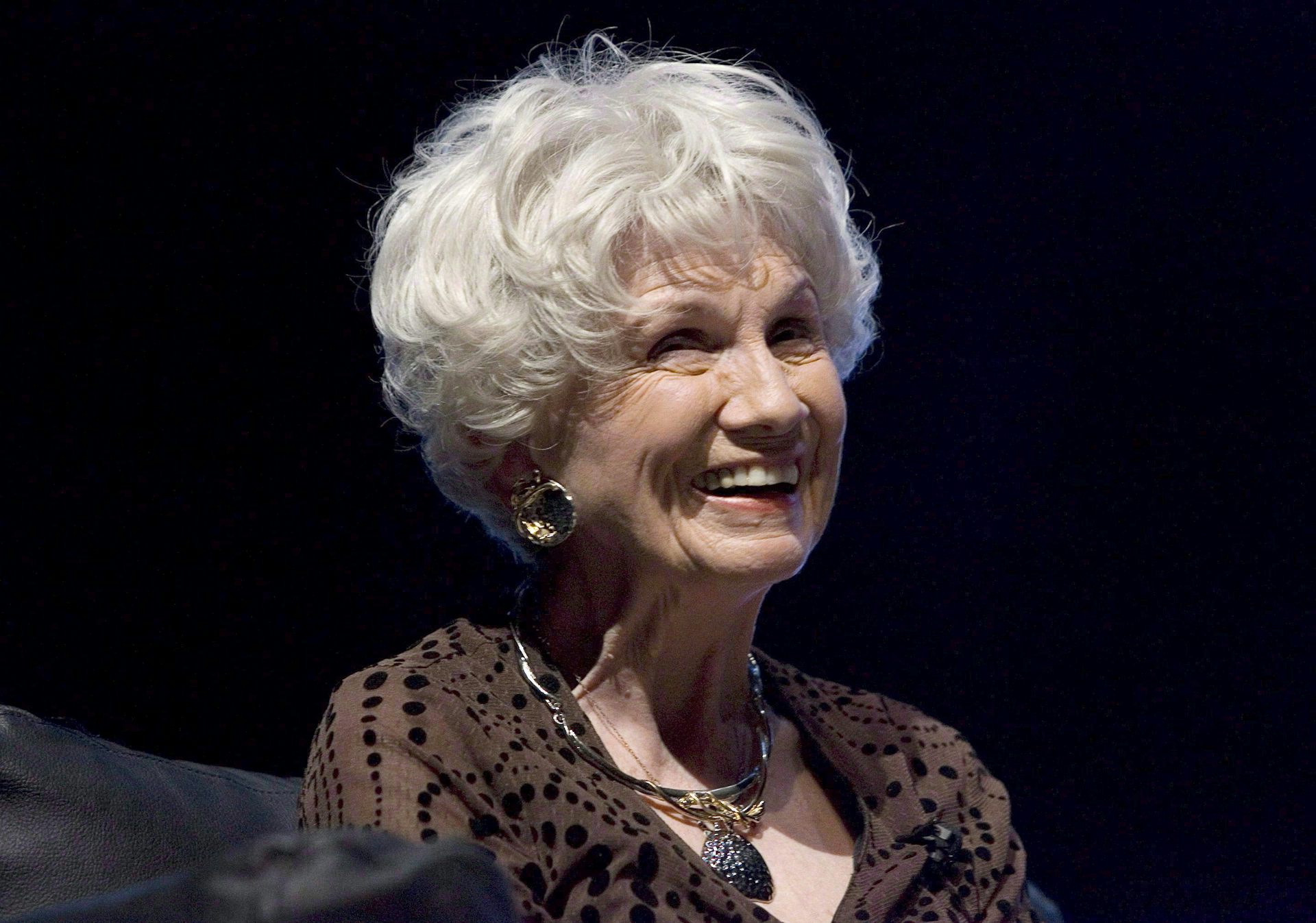 A woman smiling against a dark background.