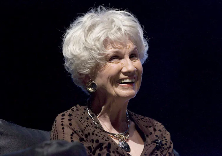 A woman smiling against a dark background.