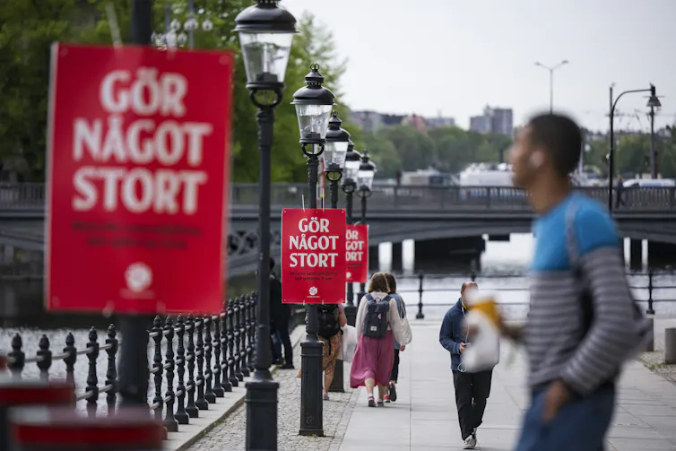 People walk by election posters in Sweden.