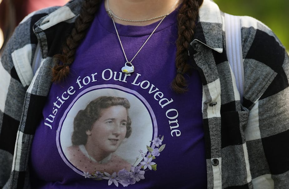 A woman wears a purple shirt with a face of an older woman on it