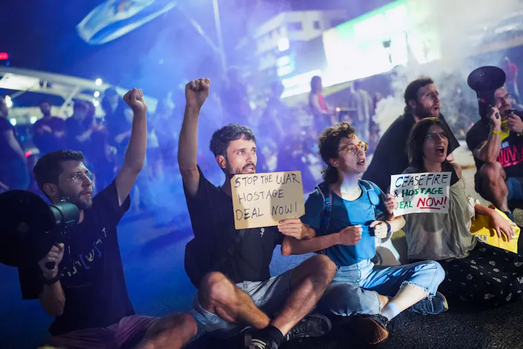 A group of Israeli hostages sat in a line holding cardboard signs calling for an end to the war in Gaza.