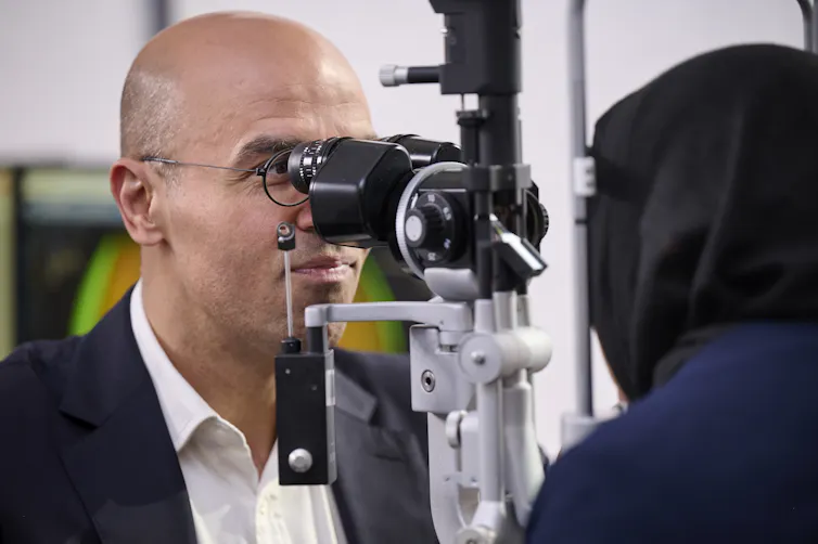 A photo of a man (the author) looking into the eye of a female patient.