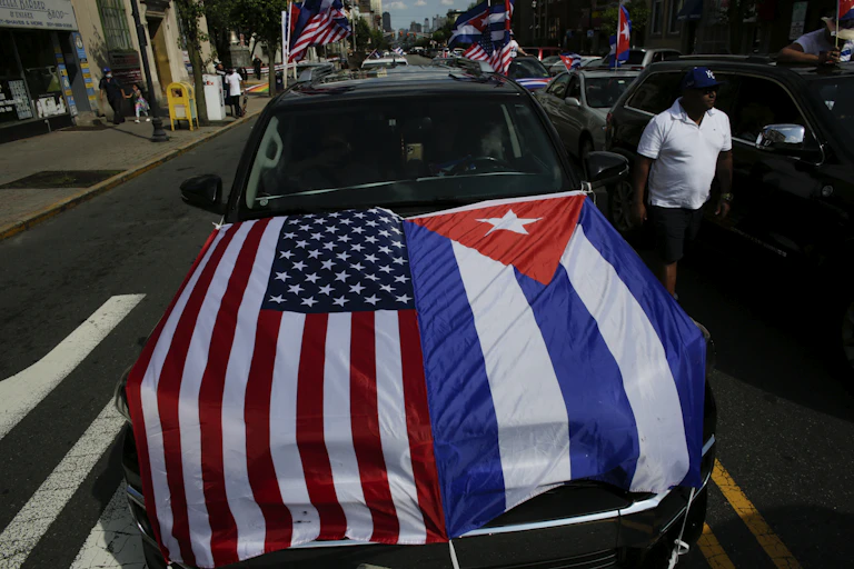 A car has the American and Cuban flags on the bonnet.