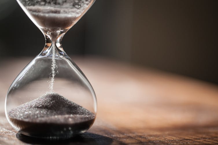 An hourglass with sand trickling from one end to the other.