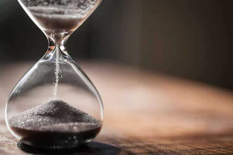 An hourglass with sand trickling from one end to the other.