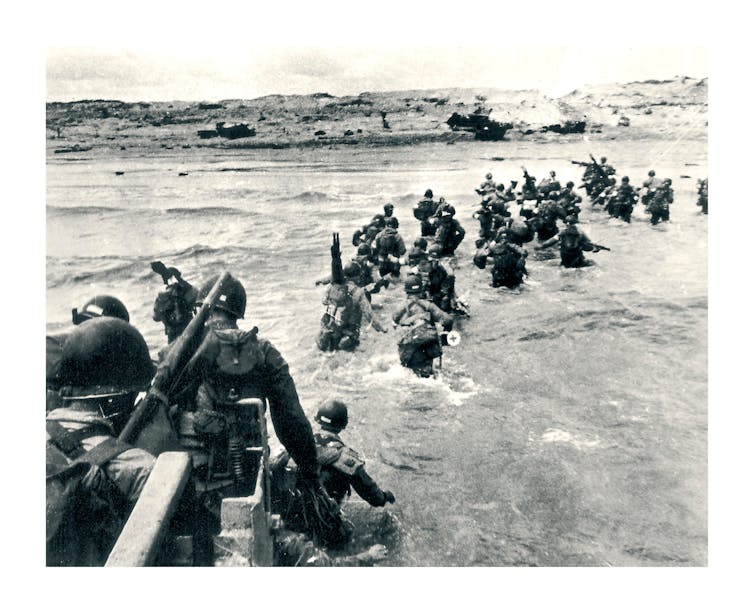Uma foto em preto e branco mostrando soldados deixando embarcações de desembarque durante o Dia D em 1944.