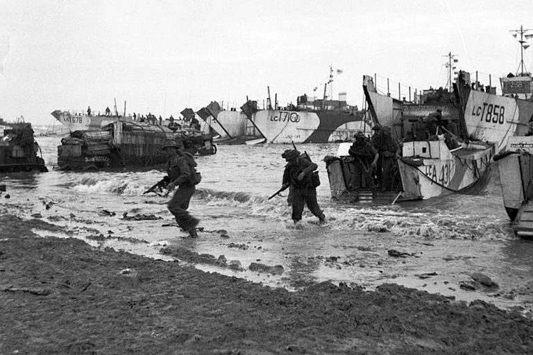 A black and white photo showing soliders coming ashore on a beach during the D-Day landings of 1944.
