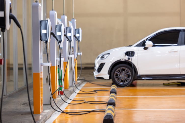 An electric vehicle parked next to a row of chargers