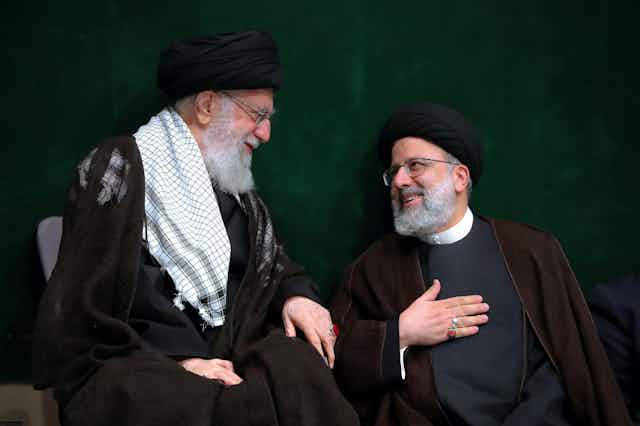 Iran's supreme leader Ayatollah Ali Khamenei, and the president, Ebrahim Raisi, smile at each other.