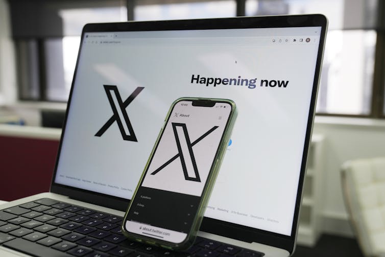 A laptop screen showing the X website behind a smartphone screen showing the same website.
