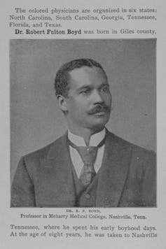 A black man in a business suit poses for a portrait.