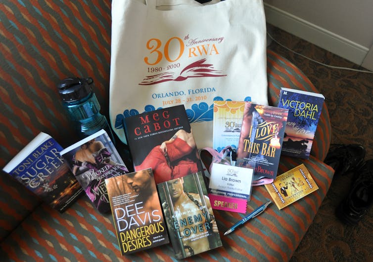Various romance books spread out on a sofa chair.