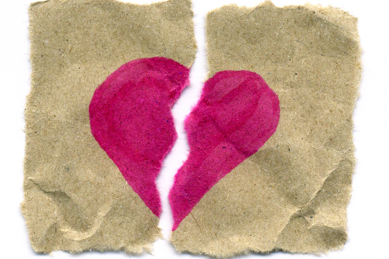 Piece of brown paper with heart painted on it, ripped in half.