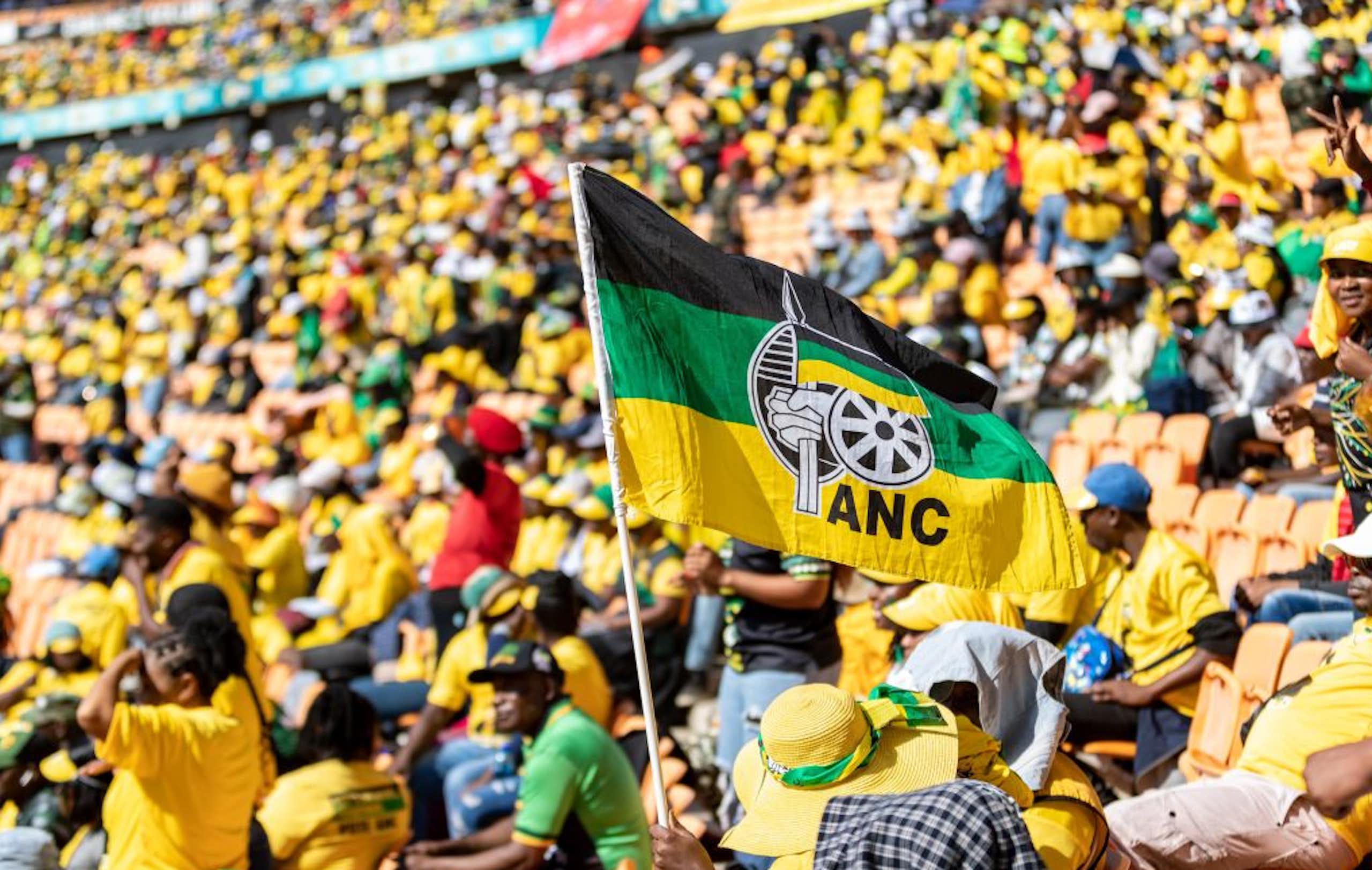 People in a stadium, many wearing yellow shirts, and a black, green and yellow flag bearing the letters ANC in the foreground