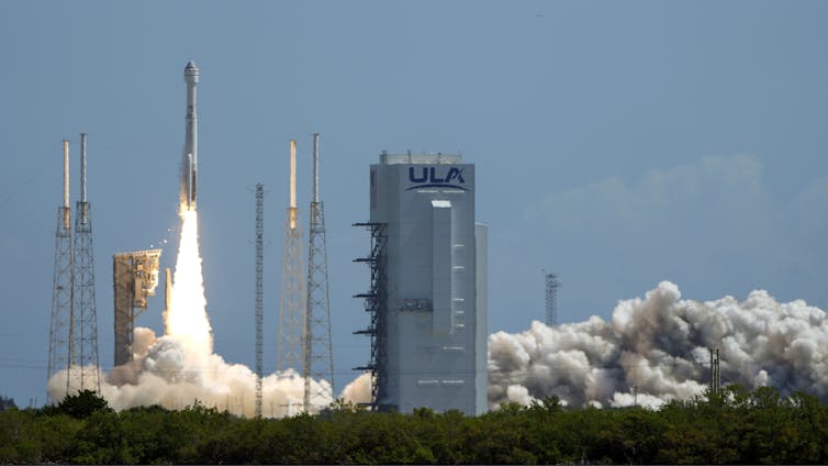 A rocket lifting off with a plume of flame and smoke below it.
