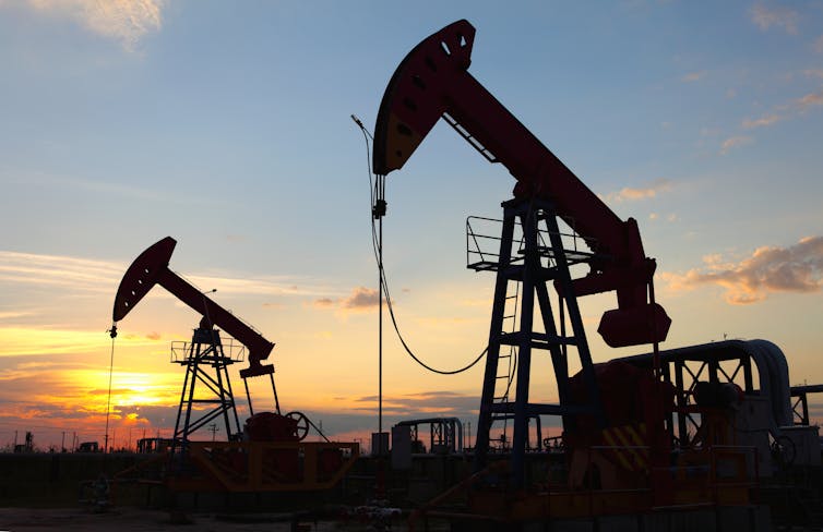 Two oil derricks at sunset.