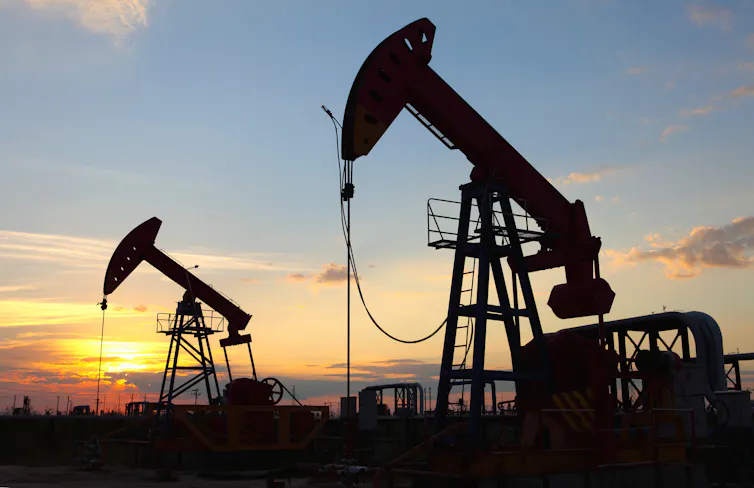 Two oil derricks at sunset.