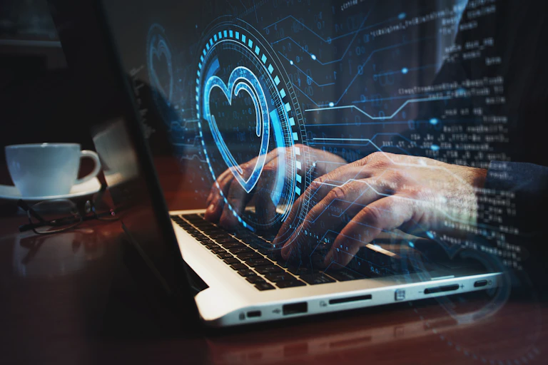 someone types on a laptop screen and a digital heart floats above the keyboard