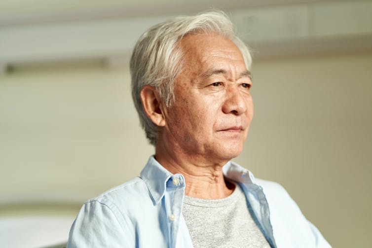 Older man of Asian background staring into distance