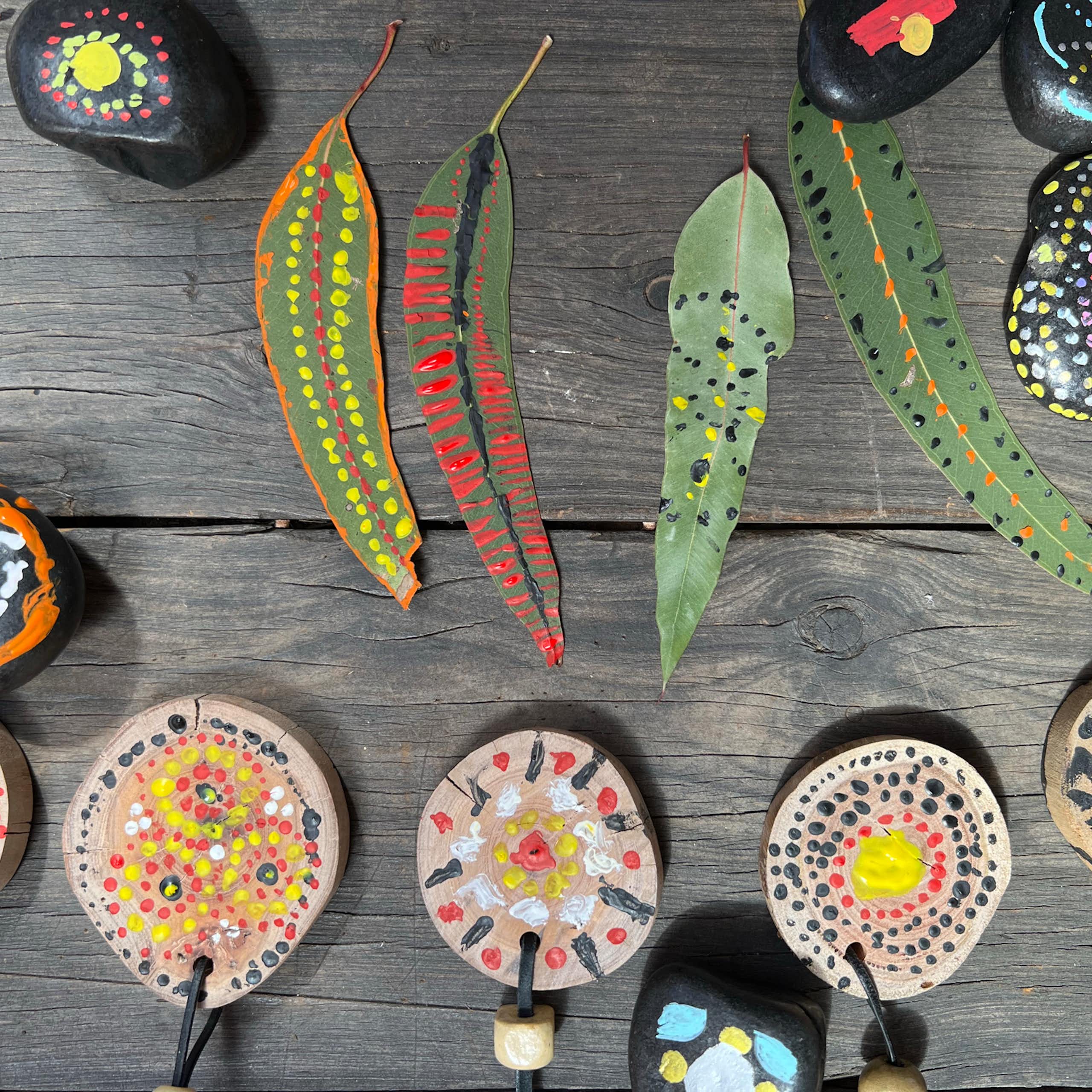  Painted, patterned Eucalyptus leaves, decorated stones and painted wooden medallions on necklaces. 