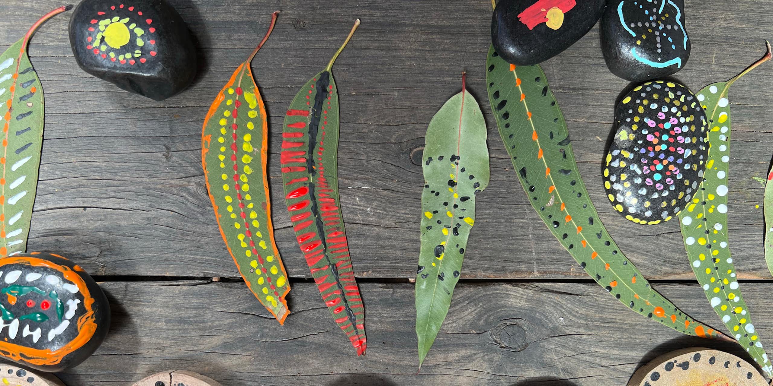  Painted, patterned Eucalyptus leaves, decorated stones and painted wooden medallions on necklaces. 