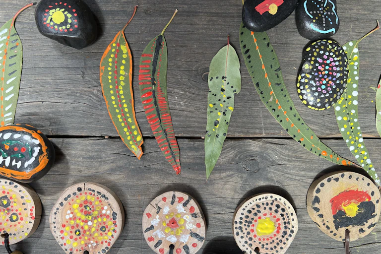 Painted, patterned Eucalyptus leaves, decorated stones and painted wooden medallions on necklaces.