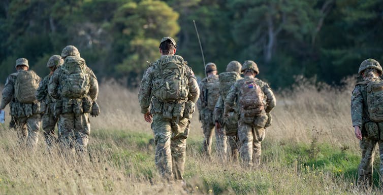 A group of army soldiers in a field walk away