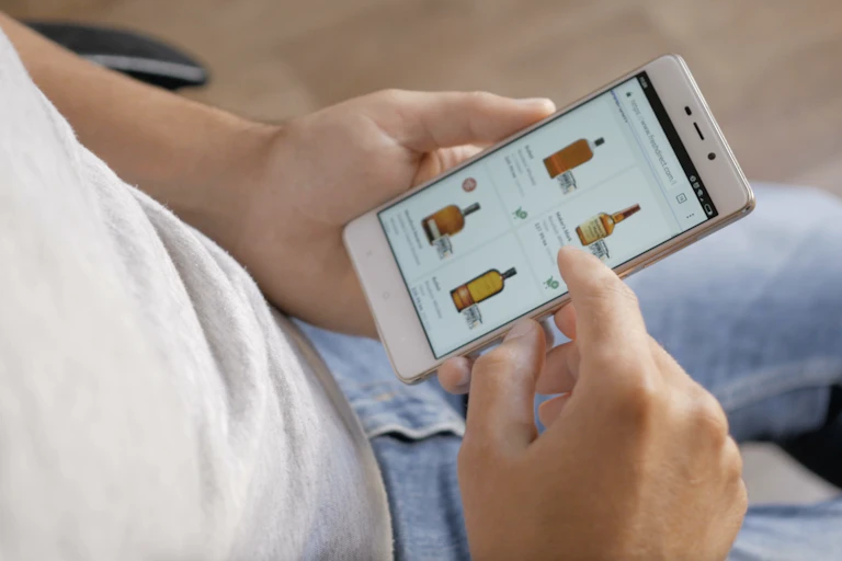 Hands holding phone browsing alcohol products