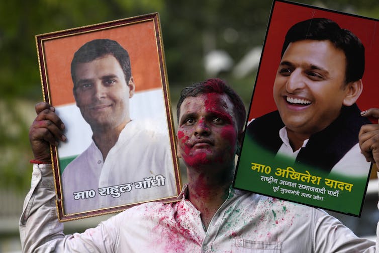 A Samajwadi Party supporter holds up two portraits.