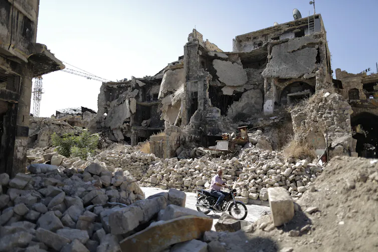 A person rides a motorbike through the rubble of Aleppo's Old City.