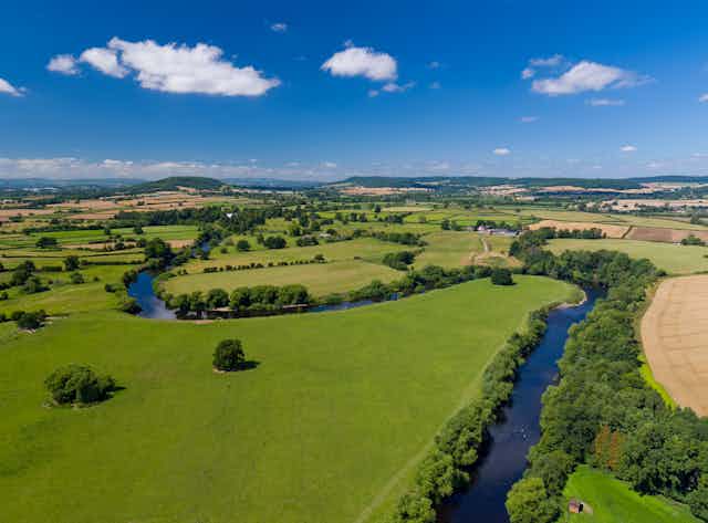 A river winds through green countryside under a blue sky.