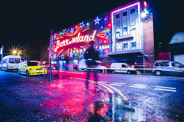 The neon-lit facade of the Barrowland Ballroom in Glasgow on a rainy night.