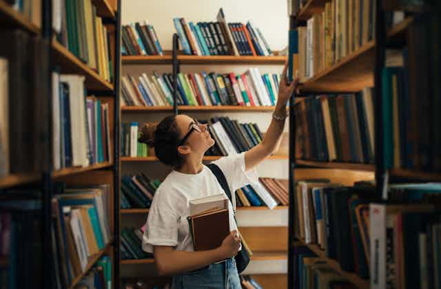 Woman looking at a library shelves. 