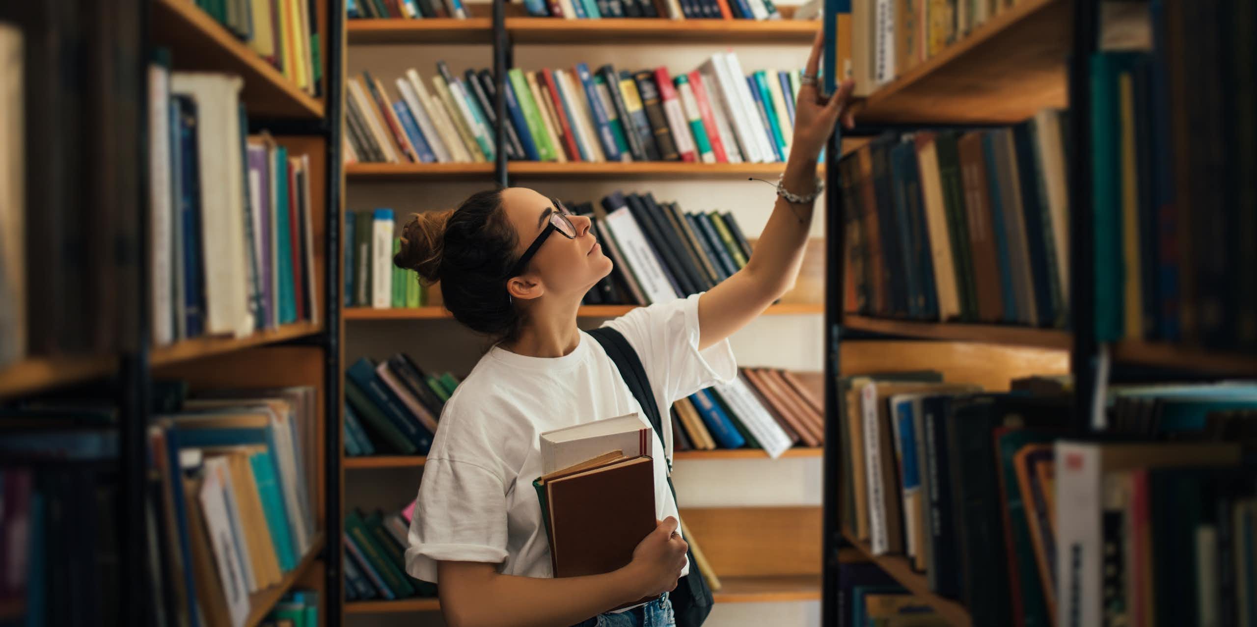 Woman looking at a library shelves. 