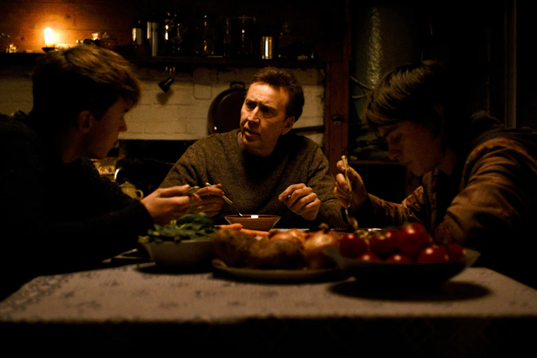 Maxwell Jenkins, Nicolas Cage, and Jaeden Martell sit around a farmhouse dinner table.