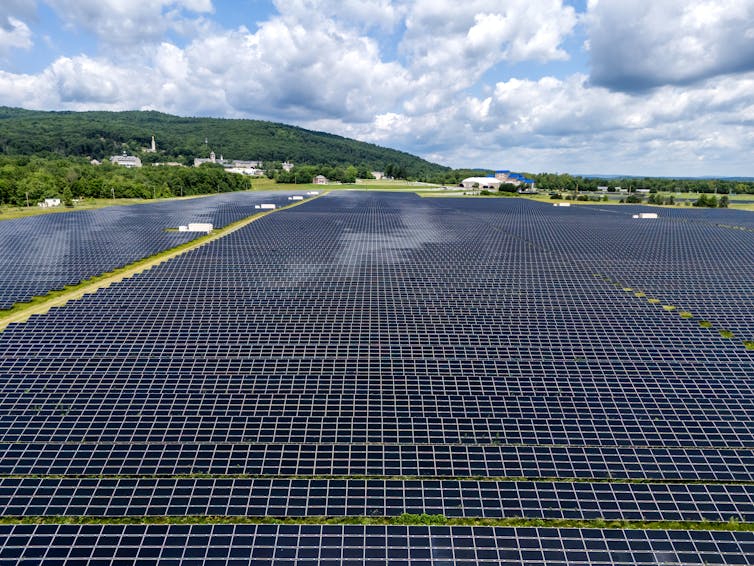Uma foto aérea de uma grande fazenda de energia solar em um dia nublado.