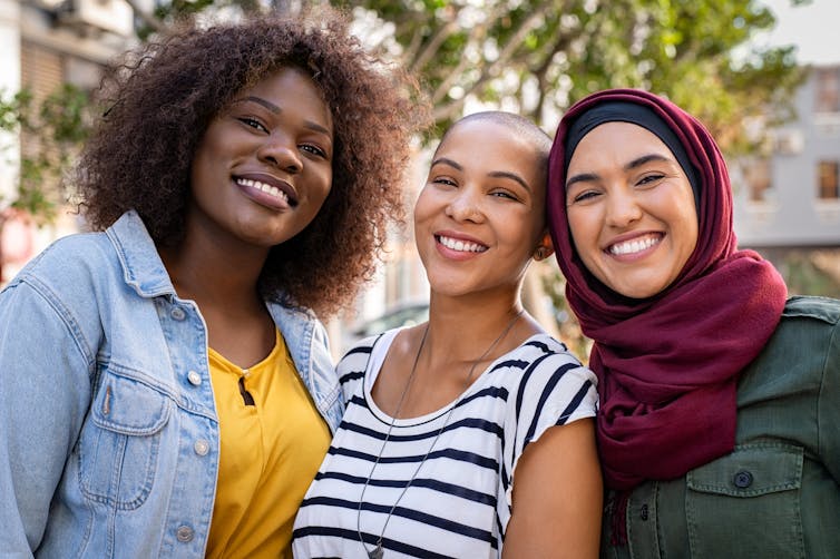 Three women of color smile.
