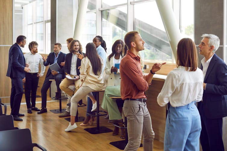 A group of people in business attire chatting in a conference room
