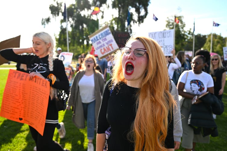 A woman chants at a rally surrounded by protestors