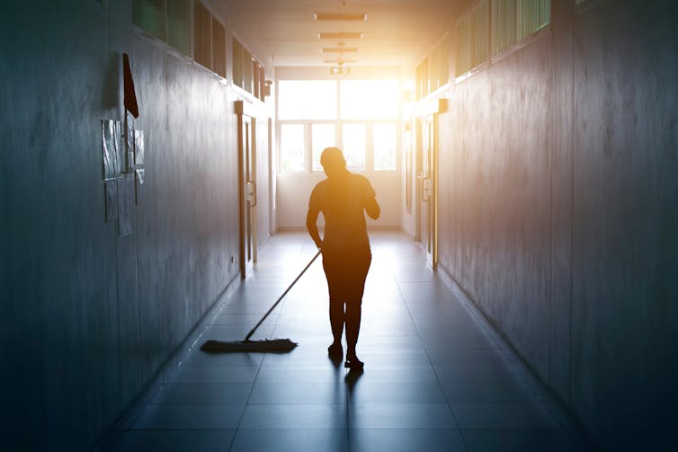 A woman mops a floor in a school.