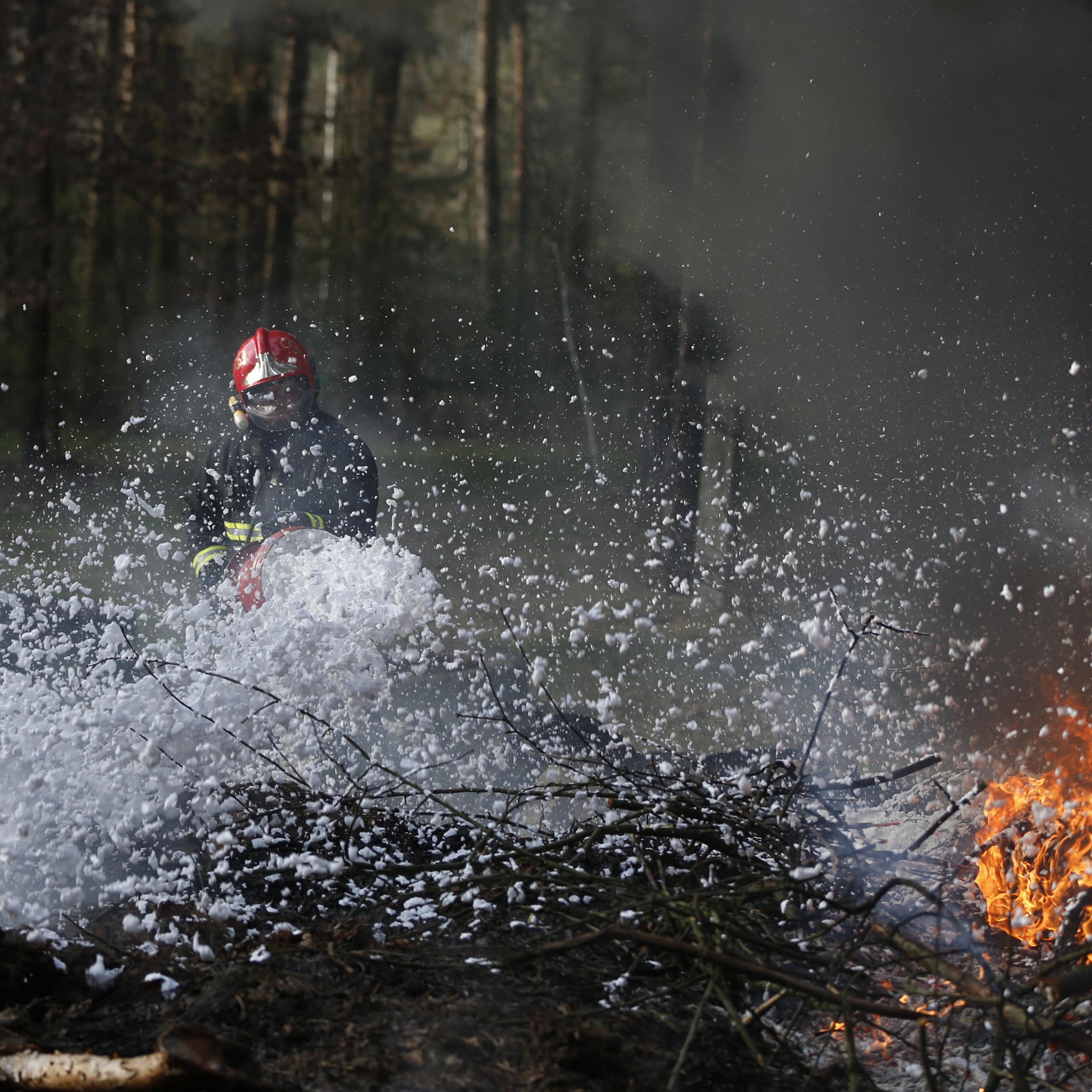 Un pompier combat un feu de forêt avec de la mousse anti-incendie.