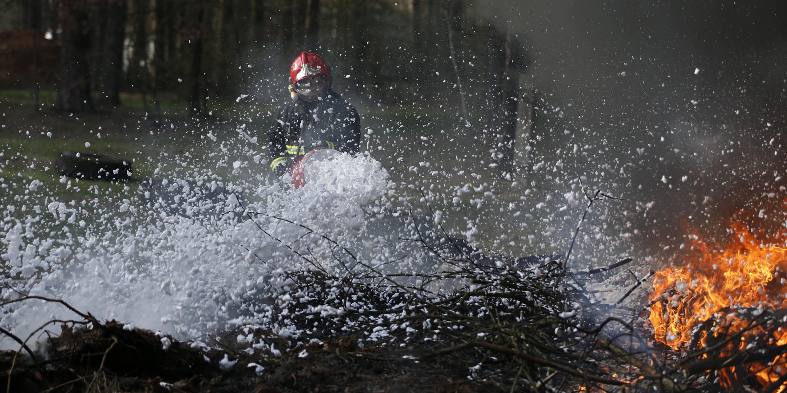 Un pompier combat un feu de forêt avec de la mousse anti-incendie.